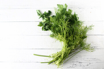 bundle of greens on white wooden background flat lay