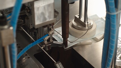 Machine for collecting medical masks in factory. The process of soldering retainer to fabric mask