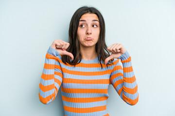 Young caucasian woman isolated on blue background showing a dislike gesture, thumbs down. Disagreement concept.