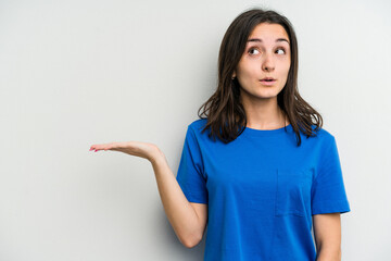 Young caucasian woman isolated on white background impressed holding copy space on palm.