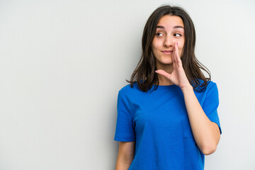 Young caucasian woman isolated on white background is saying a secret hot braking news and looking aside