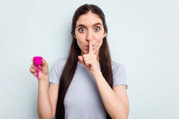 Young caucasian woman holding a sanitary napkin isolated on blue background keeping a secret or asking for silence.