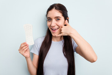 Young caucasian woman holding a sanitary napkin isolated on blue background showing a mobile phone call gesture with fingers.