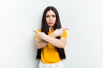 Young caucasian woman isolated on white background points sideways, is trying to choose between two options.