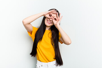 Young caucasian woman isolated on white background showing okay sign over eyes