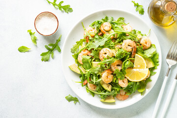 Shrimp salad with green leaves and avocado at white. Top view with space for text.