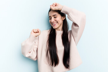 Fototapeta premium Young caucasian woman isolated on blue background celebrating a special day, jumps and raise arms with energy.