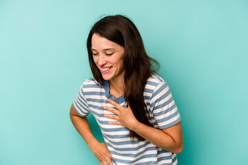 Obraz premium Young caucasian woman isolated on blue background laughing keeping hands on heart, concept of happiness.