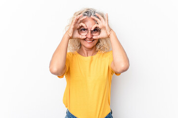 Middle age caucasian woman isolated on white background showing okay sign over eyes