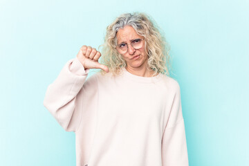 Middle age caucasian woman isolated on blue background showing a dislike gesture, thumbs down. Disagreement concept.