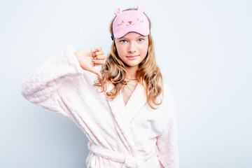 Caucasian teen girl wearing a pajama isolated on blue background showing a dislike gesture, thumbs...