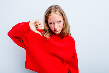 Caucasian teen girl isolated on blue background showing thumb down and expressing dislike.