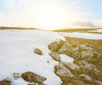mountain plateau with grass and snow at the sunset