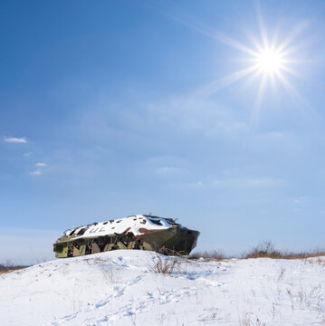damaged armored personnel carrier stay among snowbound plain at the sunny day