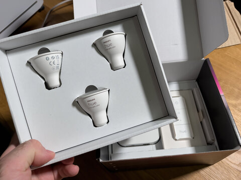 Paris, France - Dec 14, 2021: POV male hand unboxing set of new Philips Hue GU10 bulbs with white and color capabilities - smart illumination controlled by smartphones, computers and voice assistants