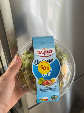 Paris, France - Dec 21, 2021: POV male hand holding package with Tuna egg salad manufactured by French company Daunat - bio-organic food with minus 50 percent discount sticker