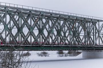 Naklejka premium Old railway bridge across the river in winter. Footprints under the bridge