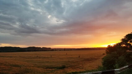 mowed wheat field at sunset in Ukraine. the sky is painted in vibrant oranges, purples, yellows and reds and hues. beauty in nature