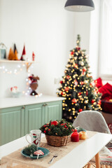In Background is Christmas Tree with Bokeh Lights. Christmas Background. Kitchen Table Decorated