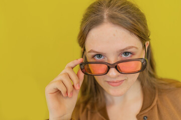 Portrait of teenage girl with acne problem of transition period on face wearing pink sunglasses on isolated background