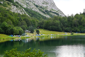 Lots of tents and campers by the lake on the mountain. Trnovacko lake and mountain Maglic, Montenegro.