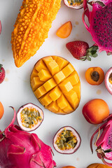 Exotic fruits on white background -  mango, dragon fruit, strawberry, passion fruit, apricot, momordika. Top view. Tropical fruits background, many colorful ripe tropical fruits.