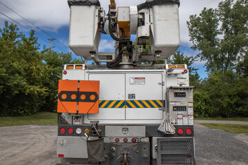 Rear view of an unmarked electrical utility hydro bucket  truck on a gravel lot, with view of baskets and boom, nobody