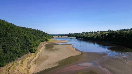 Zelfklevend Fotobehang Drone footage of aerial view over Lindley Wood Reservoir, North Yorkshire, during drought in summer 2022 heatwave. Empty reservoir basin shows cracked dry bare ground. © PhotographyBradley