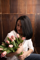 a young woman looks at pink flowers

