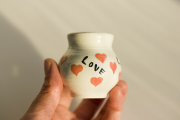 small white pot with hearts and the inscription Love. ceramic product. author's work