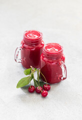 Cherry smoothie in a glass jar. Light grey background