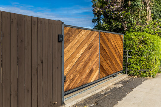 Stained natural wood modern and clean wood driveway property private gate entrance in a tropical location with secure gate access pinpad