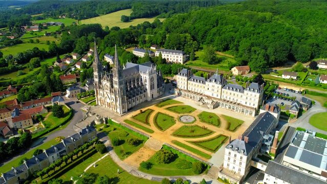Aerial Backward Shot Of Notre Dame De Montligeon Church Amidst Town Surrounded By Trees - La Chapelle-Montligeon, France