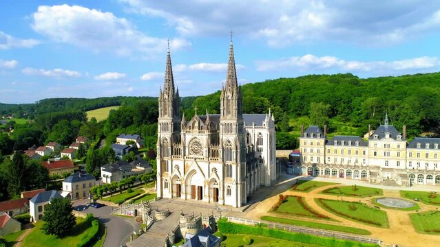 Aerial Forward Shot Of Notre Dame De Montligeon Church Amidst Houses In Town - La Chapelle-Montligeon, France