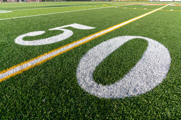 Synthetic turf football field fifty, 50, yard line in white. 
