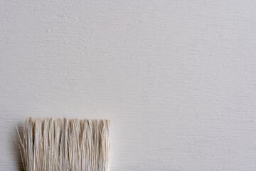detalle de brocha con pintura blanca sobre madera recién pintada  de blanco