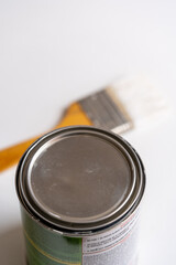 primer plano de tapa de bote de pintura con brocha en segundo plano y fondo blanco