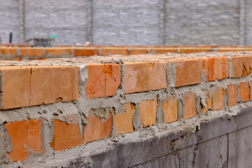 initial rows of brickwork. the initial stage of building a house. masonry of orange ceramic bricks.