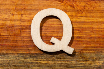 Wooden letters Q on wooden background, top view