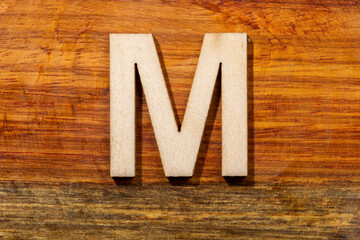 Wooden letters M on wooden background