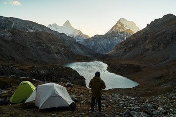 Fototapeta premium asian photographer taking a photo of mountain and lake in yading national park