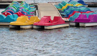 Colorful pedal boats on a lake waiting for riders
