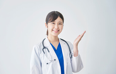 白バックで掌で右を指す女性医師