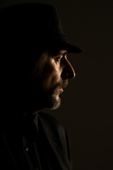Portrait of middle aged man wearing black clothes and black hat posing in the studio