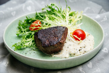 Culinary mistake. A piece of overcooked and burnt beef meat on salad leaves with cherry tomatoes...