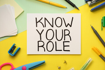 Note with phrase Know Your Role and stationery on color background, flat lay
