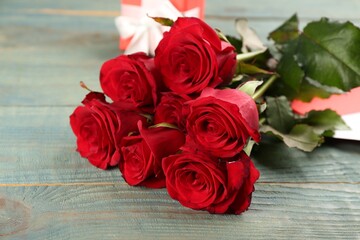 Beautiful red roses on blue wooden table, closeup. Valentine's Day celebration