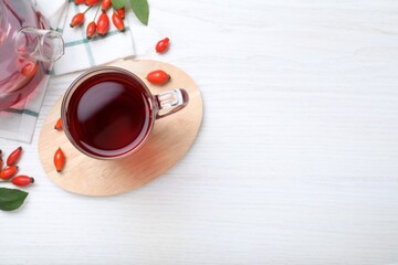 Flat lay composition with aromatic rose hip tea on white wooden table. Space for text