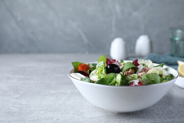 Bowl of delicious salad with canned tuna and vegetables on light grey table, space for text