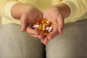 Young woman holding pile of dietary supplement pills, closeup